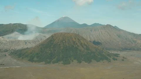 A mountain range with a volcano in the middle Stock Photos