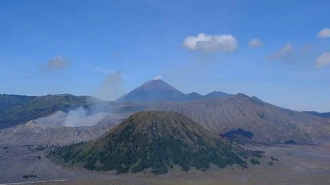 A mountain range with a volcano in the middle Stock Photos