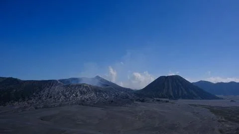A mountain range with a volcano in the middle Stock Photos