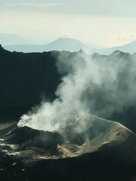 A mountain range with a volcano in the middle Stock Photos