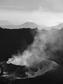 A mountain range with a volcano in the middle Stock Photos