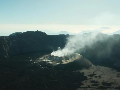 A mountain range with a volcano in the middle Stock Photos