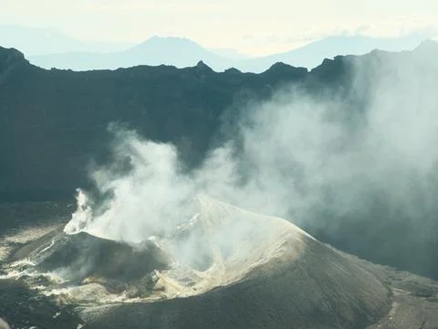 A mountain range with a volcano in the middle Stock Photos