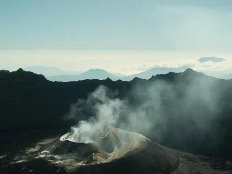 A mountain range with a volcano in the middle Stock Photos