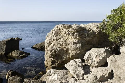 Mountain range washed by the sea on the background of the blue sky Stock Photos