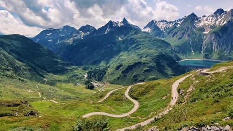 A mountain range with a winding road that leads to a lake Stock Footage 306156080