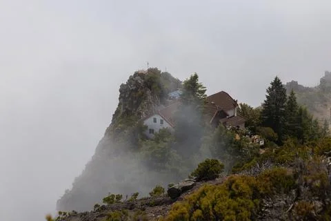 Mountain refuge surrounded by clouds and dramatic cliffs along the breathtaki Fotos de archivo