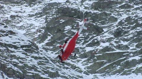 Mountain rescue. Pulling a stretcher with an accident victim into a helicopter. Stock Footage 39497506