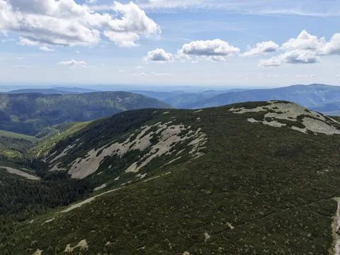 Mountain ridge with alpine shrubs under blue sky and scattered clouds Stock Photos
