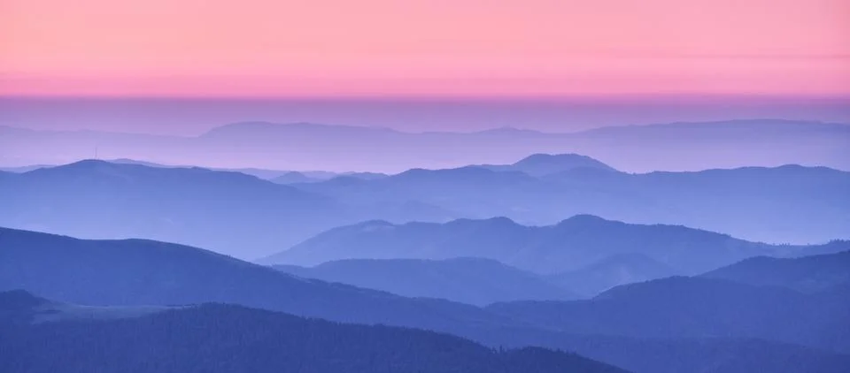 Mountain ridges in fog and pink sky at sunset in autumn Stock Photos