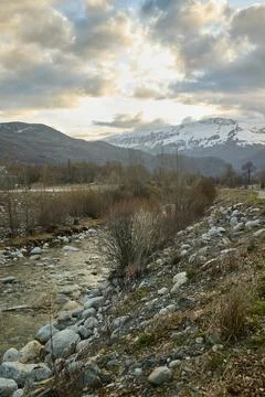 Mountain river against the backdrop of snow-capped mountains Stock Photos