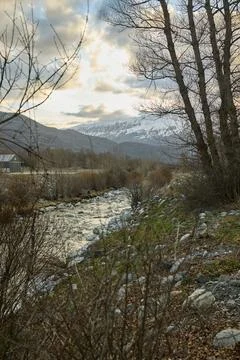 Mountain river against the backdrop of snow-capped mountains Stock Photos
