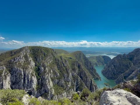 Mountain river in a canyon against a background of green forest and blue sky 写真素材