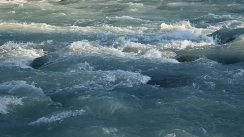 A mountain river cascades over large boulders with blue-gray colored water. Stock Footage 142707030
