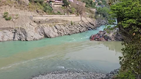 Mountain river confluence with crowded riverside ghat and hillside settlement Stock Footage 343672499