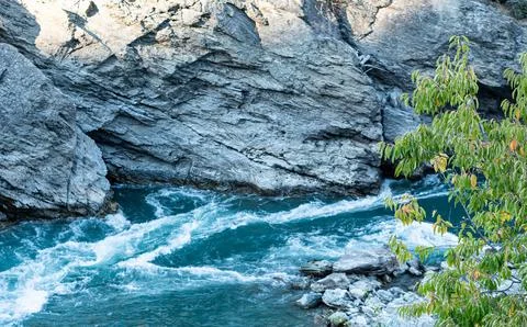 Mountain river fast flowing through cliffs rocks blue in New zealand Stock Photos
