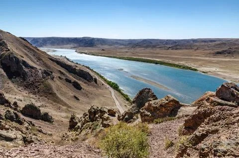 Mountain River Flowing Through Arid Canyon Valley with Rocky Slopes and Cle.. Stock Photos