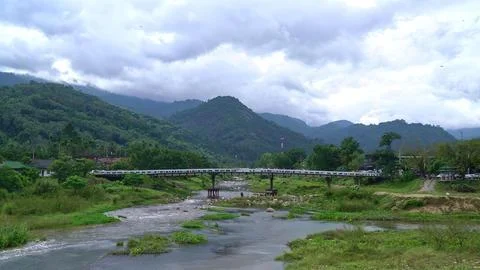 Mountain river flowing through green valley with cloudy sky 库存照片