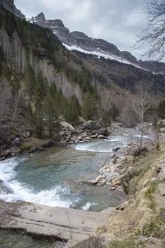 Mountain river flowing through ordesa valley with snowy peaks Stock Photos
