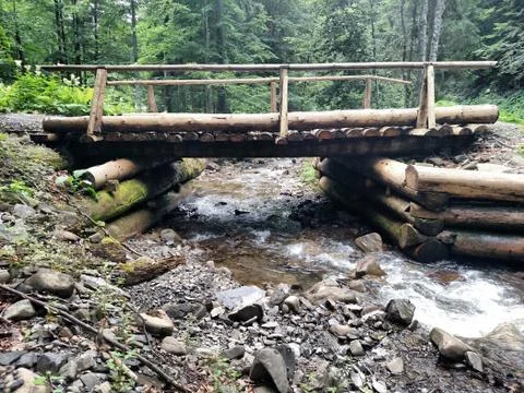 Mountain river flowing under the wood bridge Stock Photos