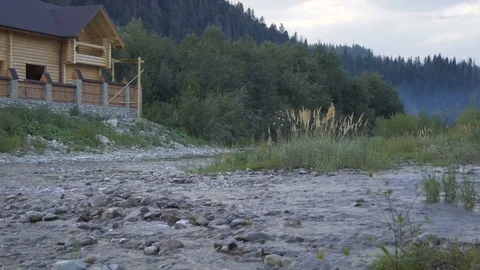 A mountain river flows along the forest and a lovely wooden house Stock Footage 79697309