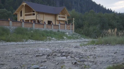 A mountain river flows along the forest and a lovely wooden house Stock Footage 79697525