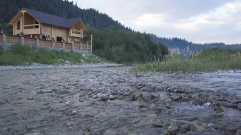 A mountain river flows along the forest and a lovely wooden house Stock Footage 79697685
