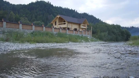 A mountain river flows along the forest and a lovely wooden house Stock Footage 79728730