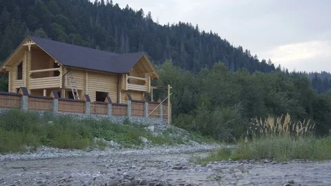 A mountain river flows along the forest and a lovely wooden house Stock Footage 79728990