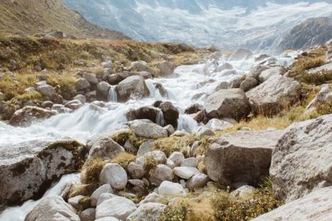 Mountain river flows between stones, background of mountains in switzerland Stock Photos