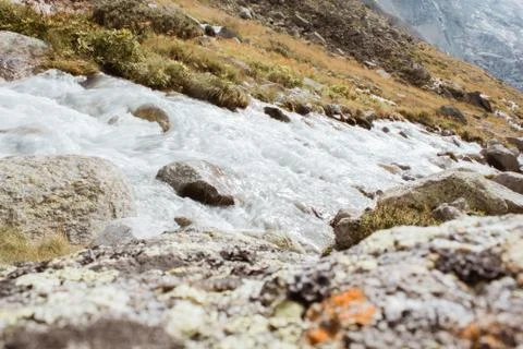 Mountain river flows between stones, background of mountains in switzerland Stock Photos