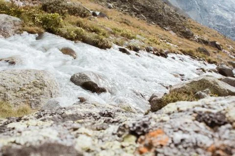 Mountain river flows between stones, background of mountains in switzerland Stock Photos