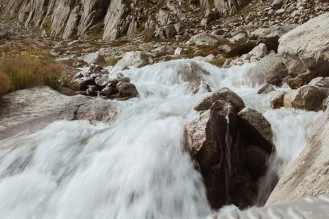 Mountain river flows between stones, background of mountains in switzerland Stock Photos