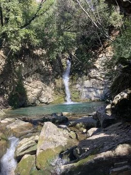 The mountain river flows down from the mountain, forming a small waterfall. Stock Photos