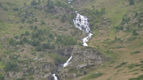 A mountain river flows down the slope into the valley Video stock 261535258