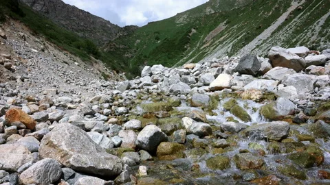 The mountain river flows from the mountains through large stones Stock-Footage 103973383