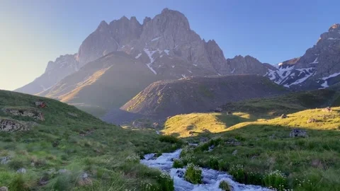 Mountain river flows through alpine grassland below Chaukhi Mountain Stock Footage 340388340
