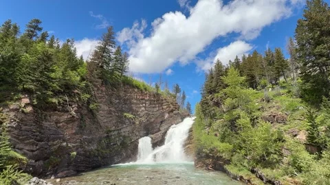 Mountain river flows through trees in landscape with snow-capped peaks  Stock Footage 338284878