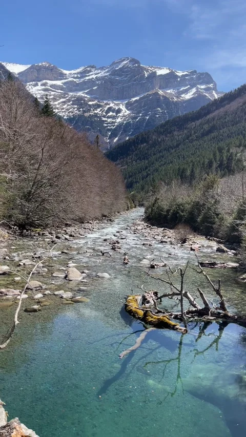 A mountain river flows through the valley between the snow capped mountains Stock Footage 238638285