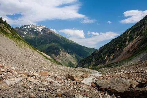 Mountain river flows through the valley. Stones lie on the banks of the river Stock Photos
