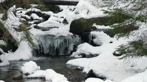 A mountain river, icicles hanging over the stream and a lot of snow. Mountain Stock Footage 274252419