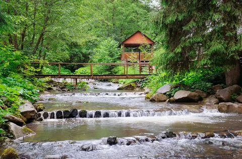 Mountain river, lush vegetation and recreation area with a bridge and gazebo. Stock Photos