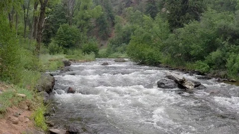 Mountain river pan down, wide shot of river to close up of splashing whitewater. Stock Footage 93493720