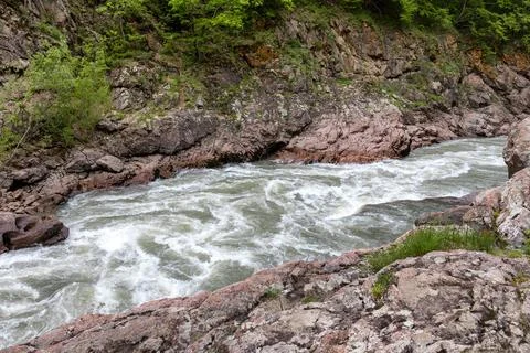 A mountain river with a rapid flow and an unusual stone bed and waterfalls in Stock Photos