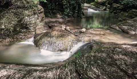 A mountain river with rapids and randomly scattered stones on its banks. Stock Photos