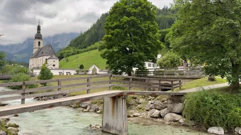 Mountain river runs through Ramsau town. Parish Church of St. Sebastian. Germany Vídeos de archivo 341423531