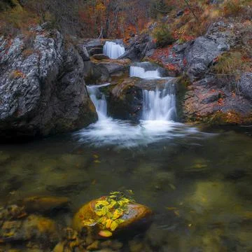 Mountain river with small waterfall with clear water falling down wet boulders Stock Photos