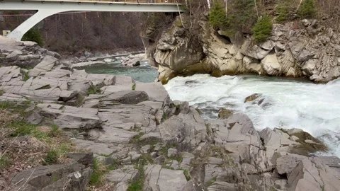 Mountain river under bridge flowing through rocky terrain in spring Stock Footage 313848449