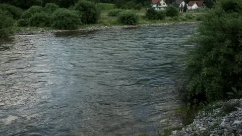 Mountain river in village. camera panning from the river to the mountains. Stock Footage 245334773