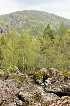 A mountain river waterfall flows through a river bed through huge boulders with 写真素材